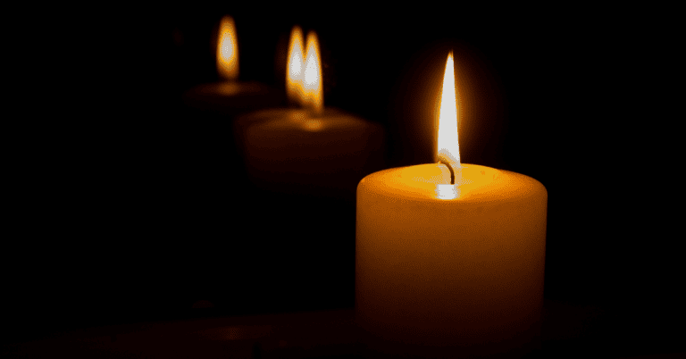 Three candles are lit in a dim room.