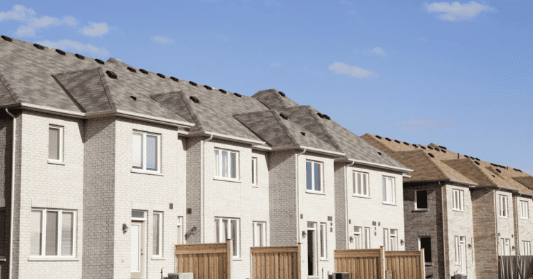 A row of townhouses against a sunny sky.