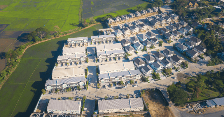 An aerial view of a neighbourhood of houses beside a farm field.