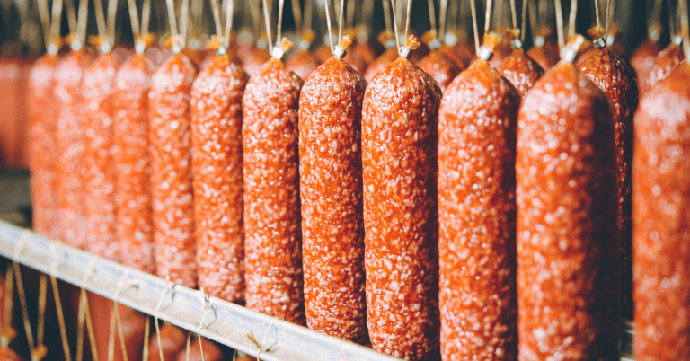 Sausages hanging on a rack in a factory.