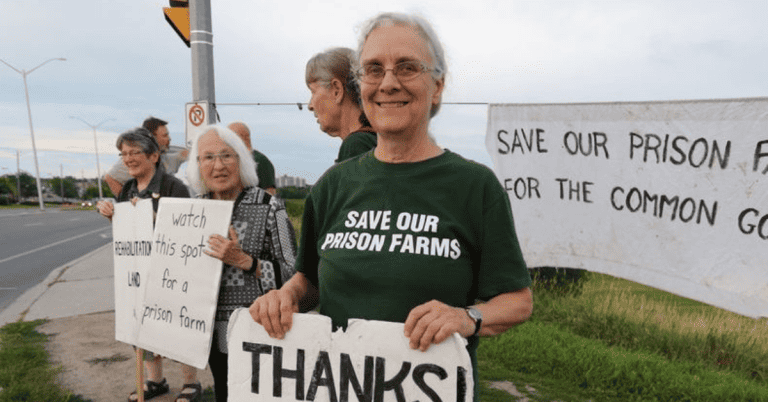 A group of people holding signs and wearing t-shirts that say save our prison farms.