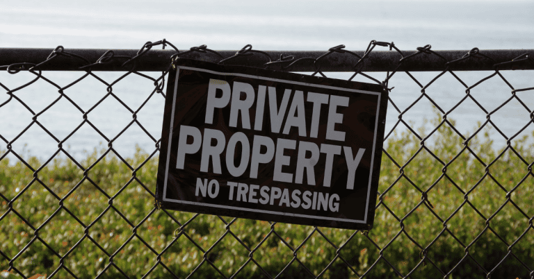 A sign on a chainlink fence that says "private property no trespassing".