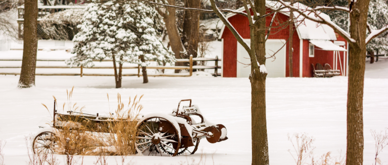 A red barn and wagon in the snow.