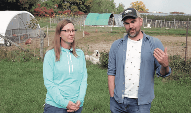 A man and woman standing in front of a chicken coop.