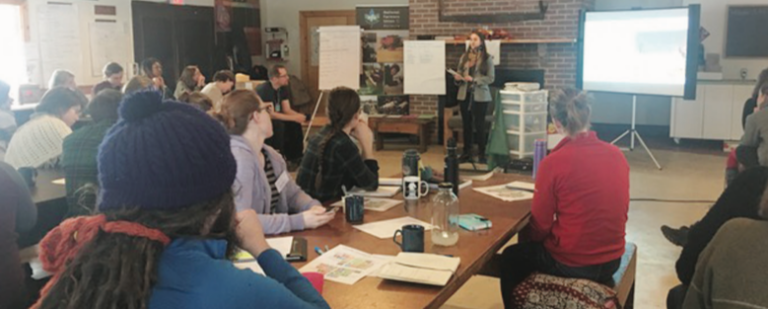 A group of people sitting at tables and watching a presentation.