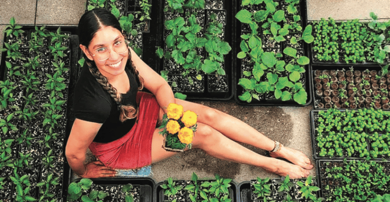 Rav Singh sitting on the ground with trays of plants.