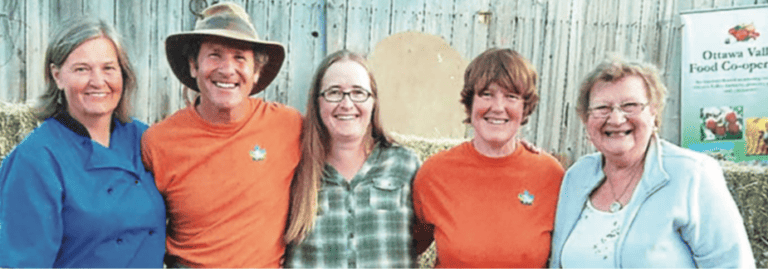 A group of people posing for a photo in front of hay bales.