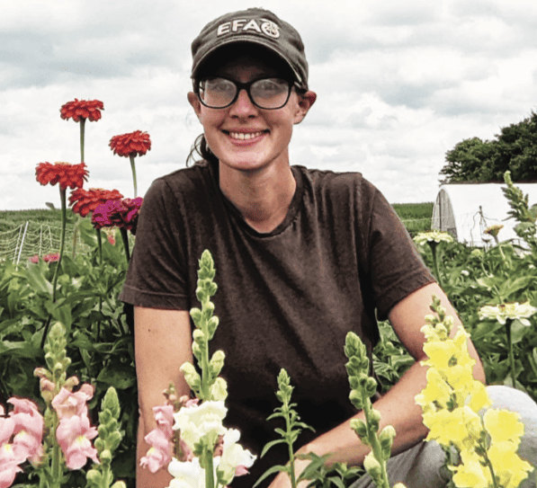 Claire Poulton sitting in a field of flowers.