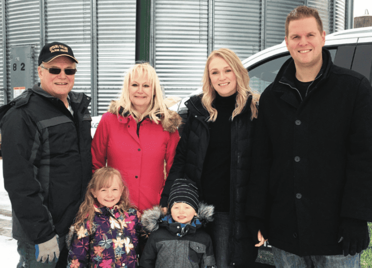 A family posing in front of a grain silo.