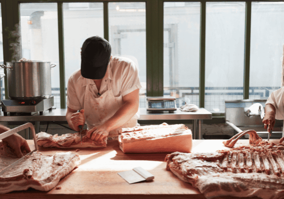 A group of people preparing meat in a kitchen.