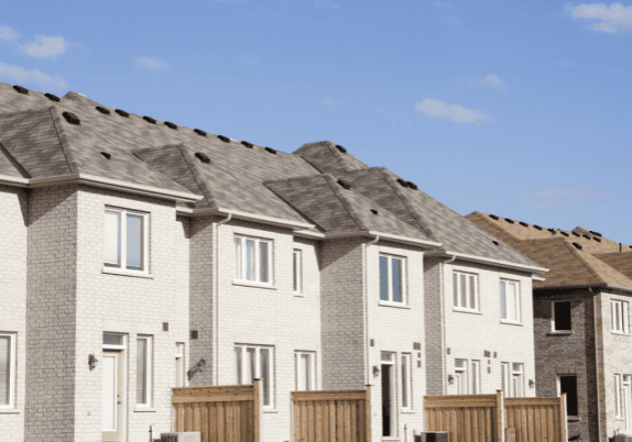 A row of townhouses against a sunny sky.