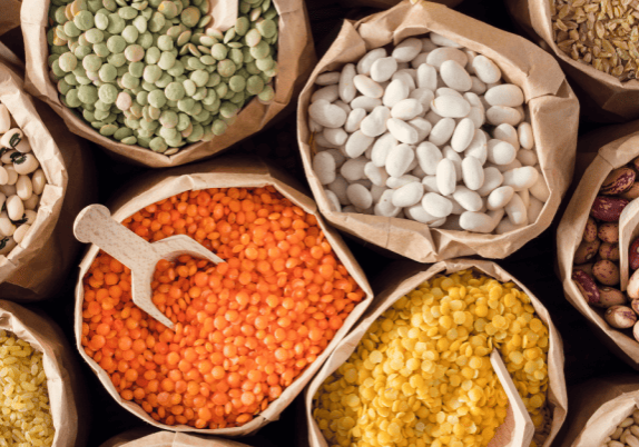 An aerial view of a variety of different types of seeds, beans and legumes in brown paper bags.