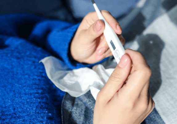 A person's hand holding a thermometer.