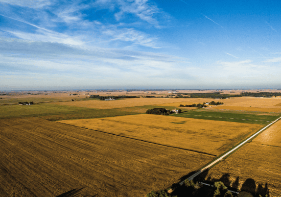 A view of farmland against the horizon with blue skies.