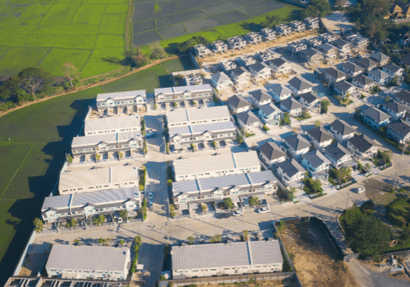 An aerial view of a neighbourhood of houses beside a farm field.