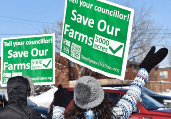 A group of people holding signs that say save our Ontario farms.