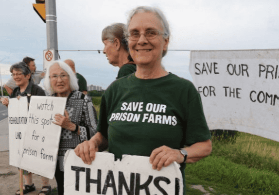 A group of people holding signs and wearing t-shirts that say save our prison farms.