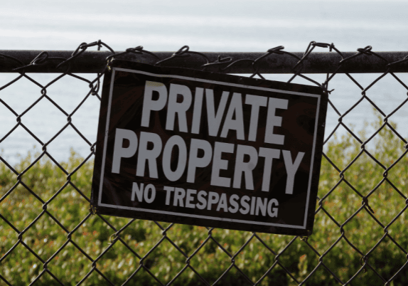 A sign on a chainlink fence that says "private property no trespassing".