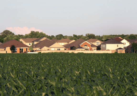 A residential area (background) bordering a farm field (foreground).