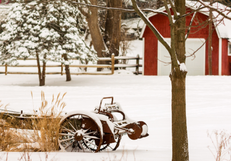 A red barn and wagon in the snow.