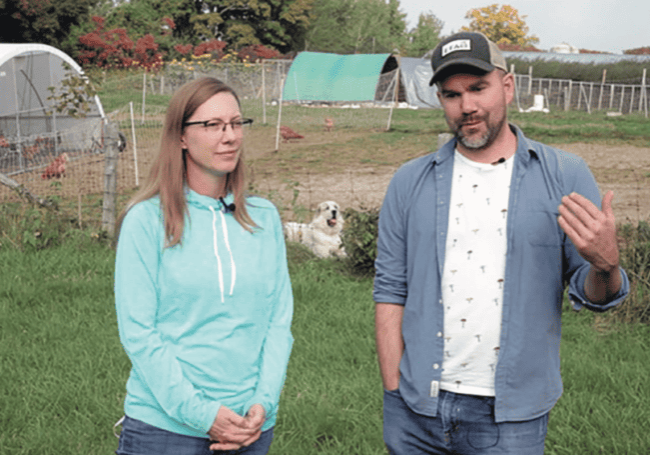 A man and woman standing in front of a chicken coop.