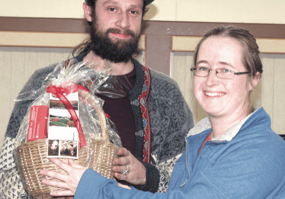 A man with a beard and a woman with glasses holding a basket.