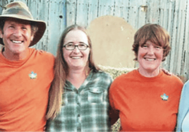 A group of people posing for a photo in front of hay bales.