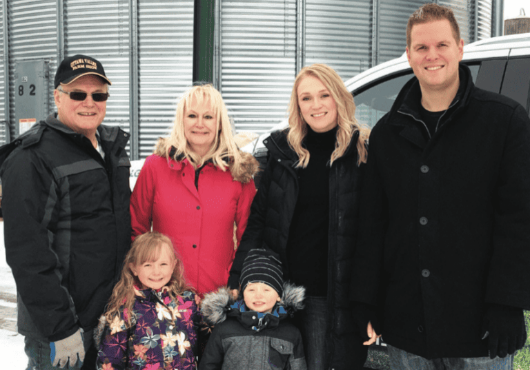 A family posing in front of a grain silo.